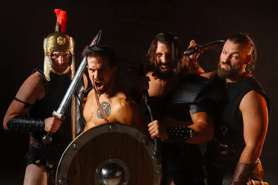 Four gladiators with swords, shields and axes roaring at the camera